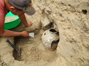 Image showing a worker uncovering a pottery vessel during excavation