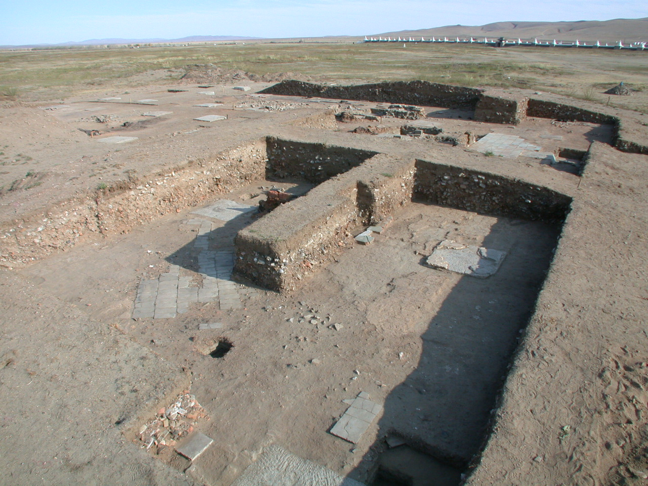 Picture showing an excavation. In the excavation, granite column bases and remains of brick-paved floors can be seen.