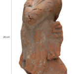 Upper body of a Galbinga with a robe/cloth draped around the shoulders, arms bent in front of the upper body and wing attachments on the back, in profile view.